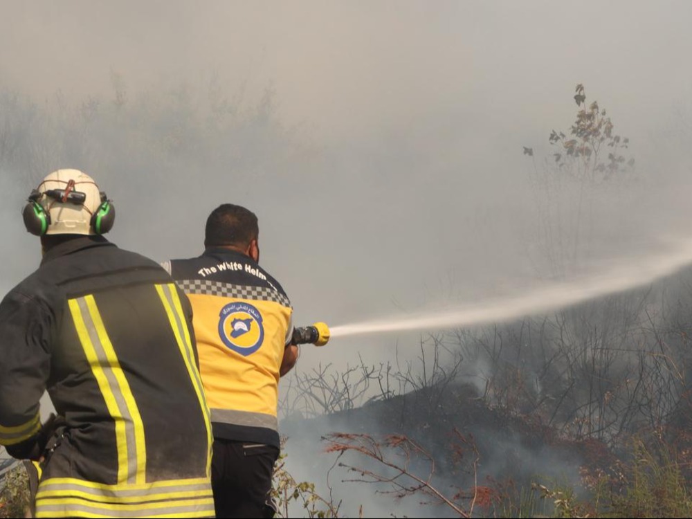 متطوعان في الدفاع المدني السوري أثناء إخماد حريق في غابات ريف اللاذقية